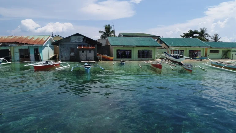 A picture of boats on a body of water bordering island houses