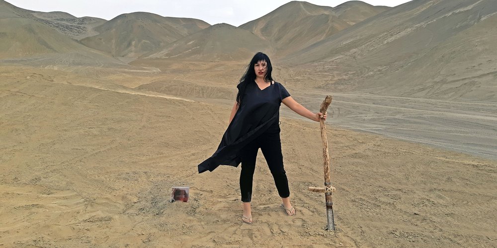 A woman in a desert holding a staff