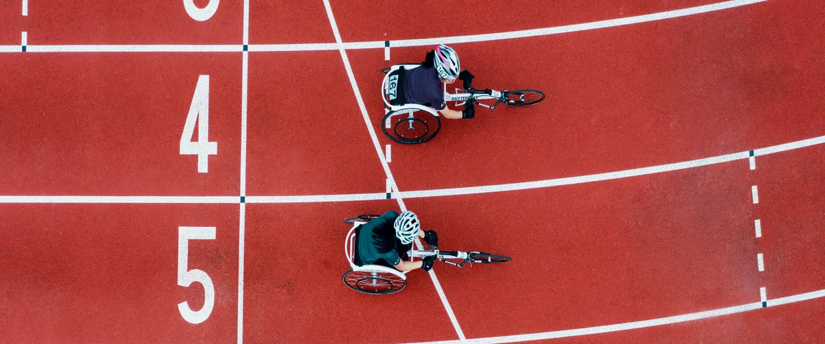 Overhead photograph of a track with two wheelchair paralympians racing.