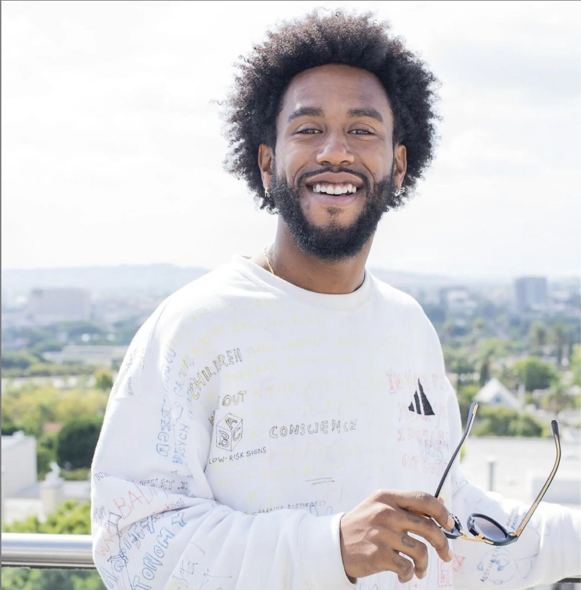 Image shows a person wearing a shirt, long sleeve t-shirt, smiling and looking into the camera.