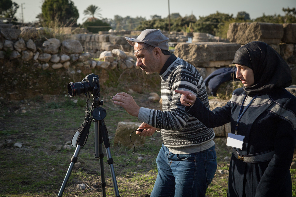 Two people standing behind a camera at the Temple of Eshmun.