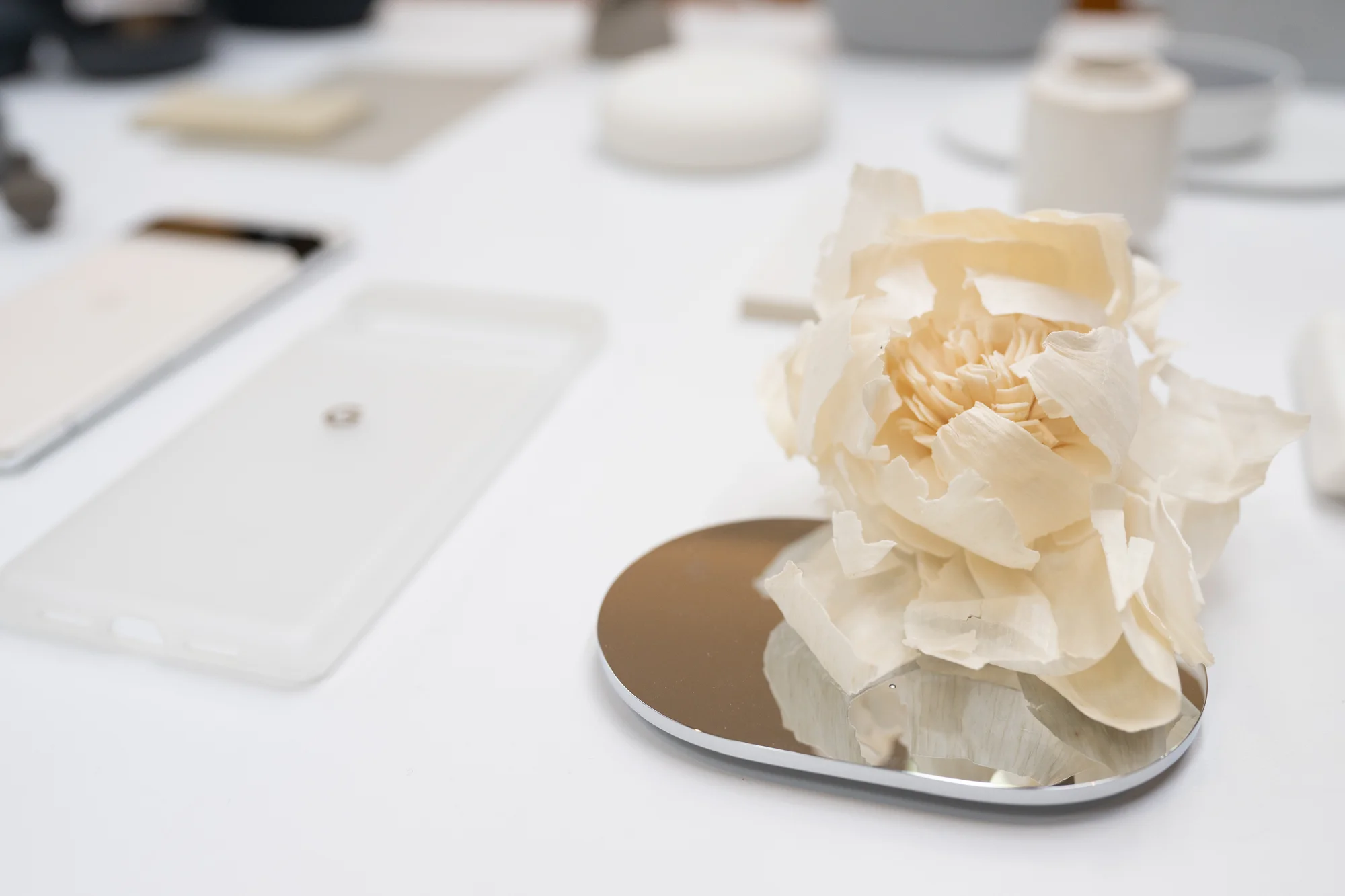 Photograph of the frosted white Pixel 6 case next to various items of shades of white, including a paper flow.