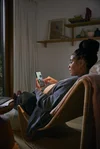 A woman looks at her Pixel phone while sitting in the living room.