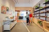 A photo of two women looking at cards and small goods on three display shelves in the Pop-Up Shop.