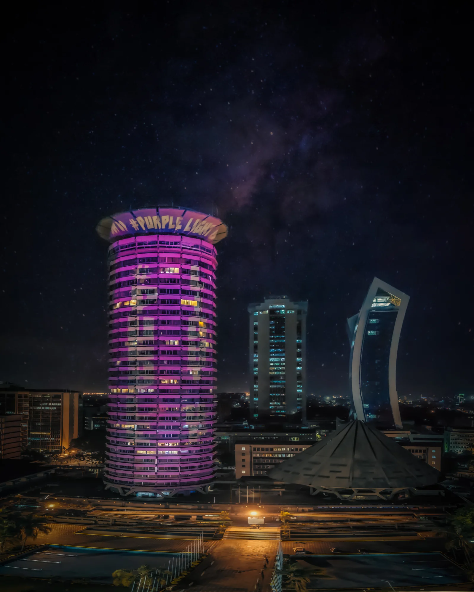 Das Kenyatta International Conference Center in Nairobi, Kenia. es ist lila beleuchtet und um das oberste Stockwerk des runden Gebäudes steht in weißer Schrift #PurpleLightUp.
