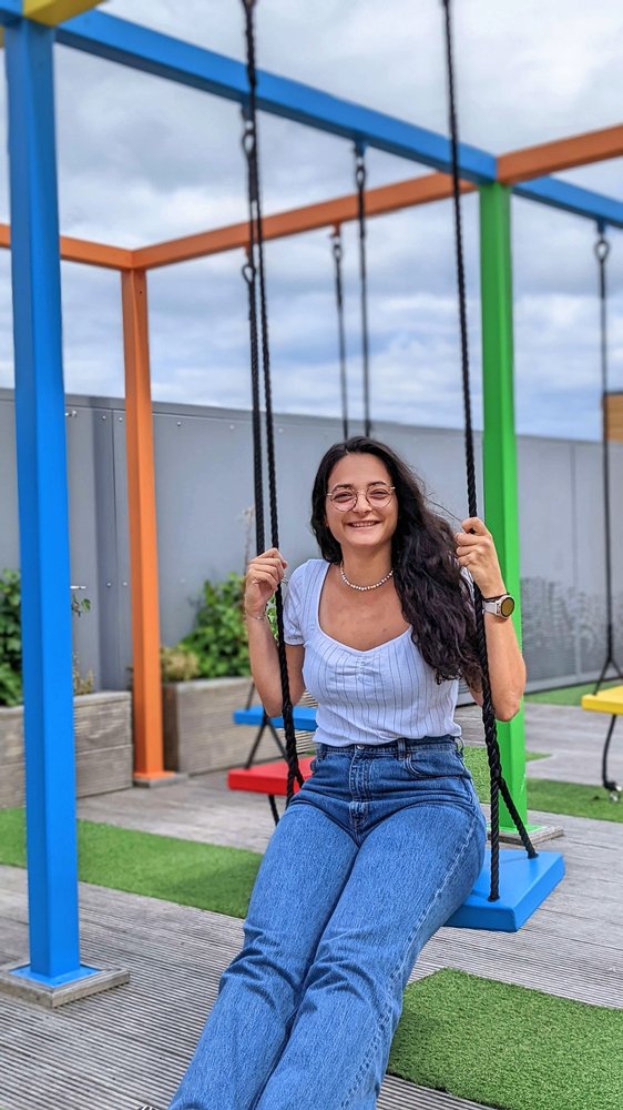 Lauriane, the interviewee, sitting on a swing and holding the swing ropes with two hands