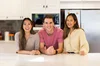 Three people standing behind a kitchen counter and smiling.