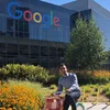 Reza outside on a Google bike in from of the Google sign at headquarters.