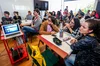 Pessoas sentadas acompanham aula em uma sala.