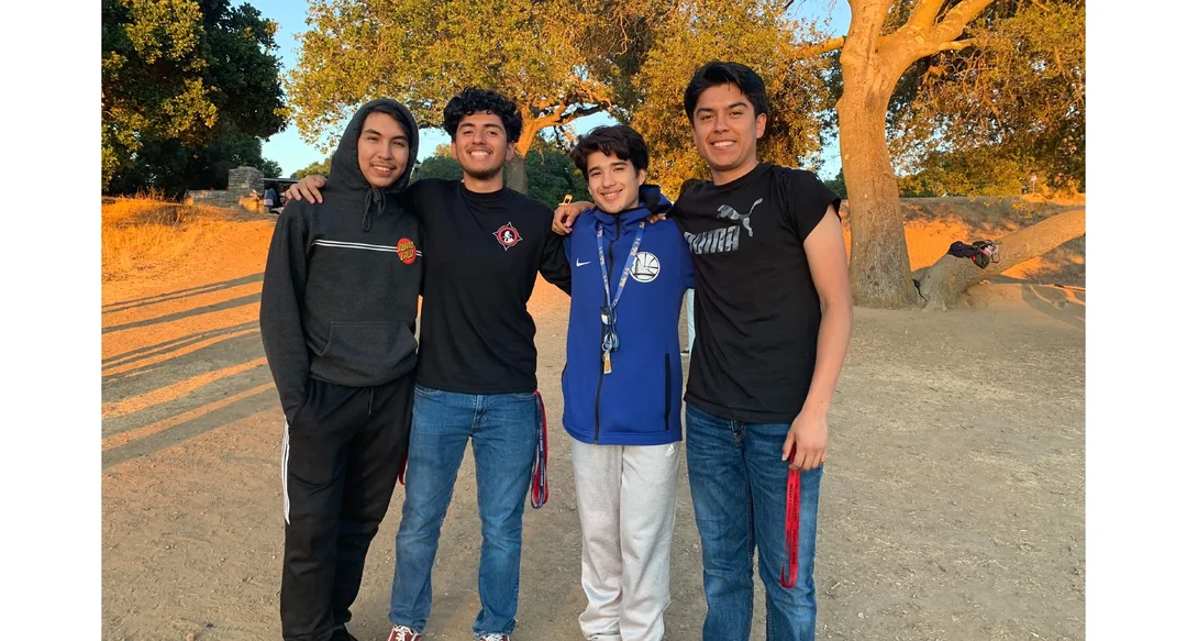 Salvador Avelar stands with 3 other students in a park setting