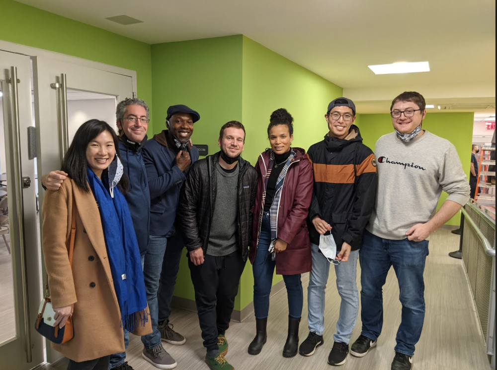 A group of people standing in a line in a medical center, looking into the camera and smiling.