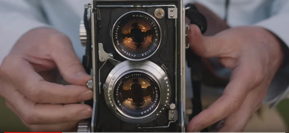 An image of two hands near an old-fashioned camera.