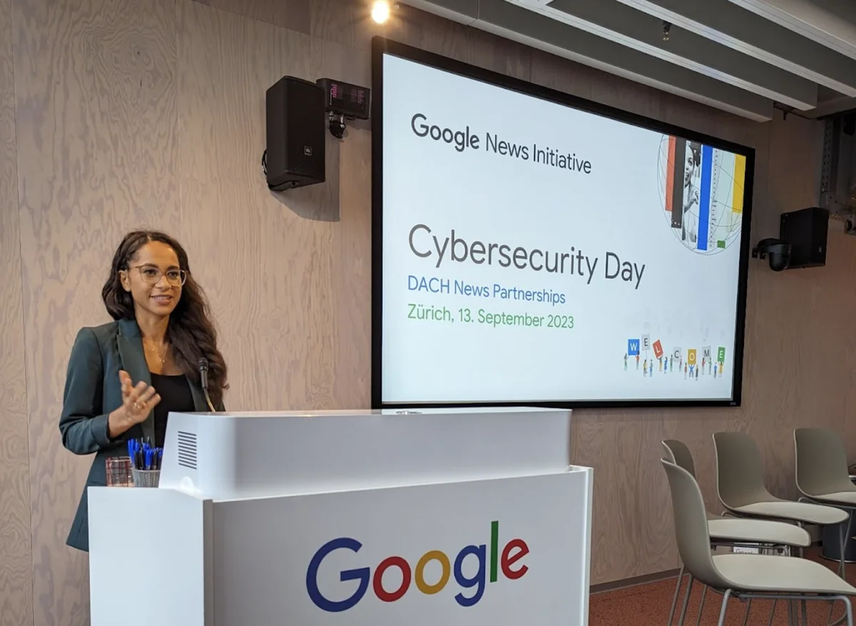 Frau am Podium, daneben ein Bildschirm mit der Überschrift Cybersecurity-Day