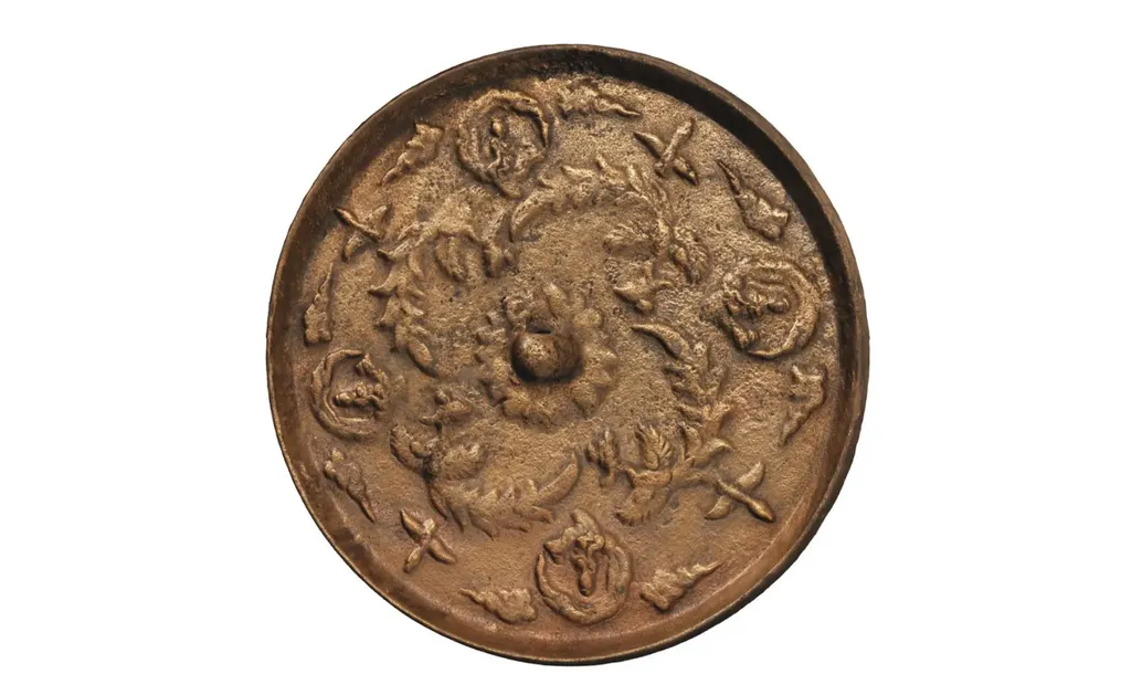 A bronze circle with reliefs of lotus flower, phoenixes, and buddhas.