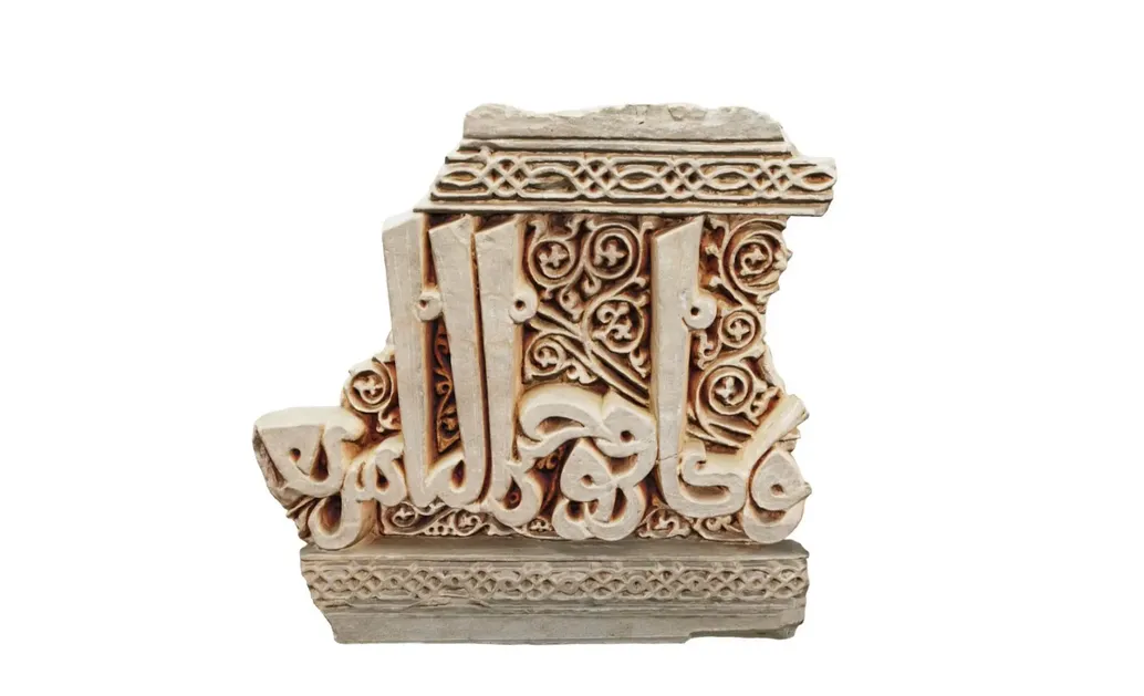 A clay embossed inscription, broken fragment outlined from top and bottom with decorative patterns, with long kufi calligraphy inscriptions in the middle.