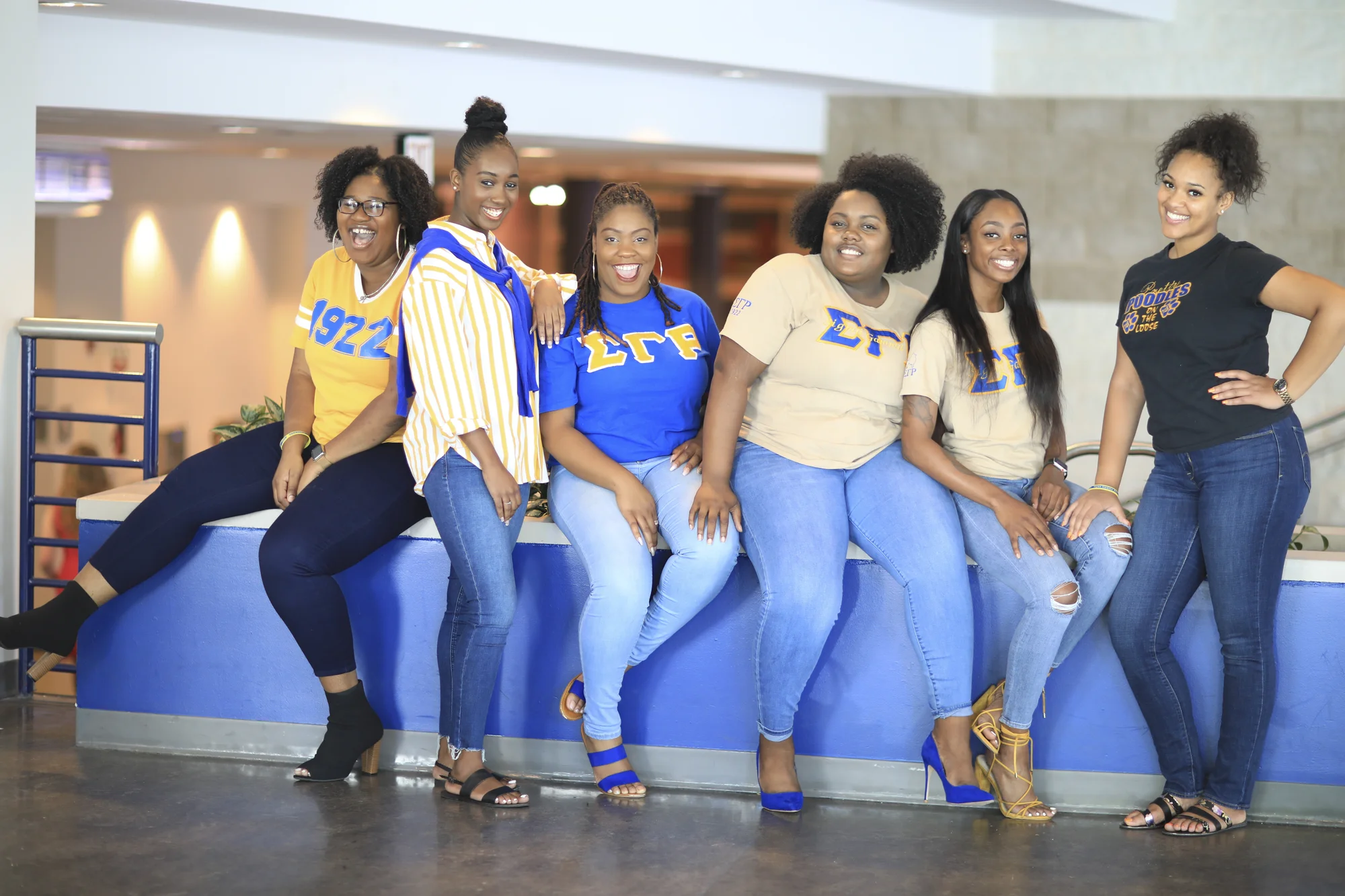 Six women in jeans and blue and yellow Sigma Gamma Rho sorority apparel