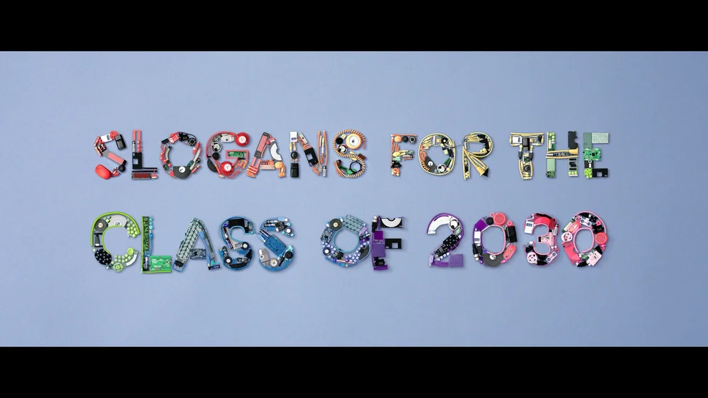 The phrase “Slogans for the class of 2030” written out using technical equipment in a rainbow of colors.