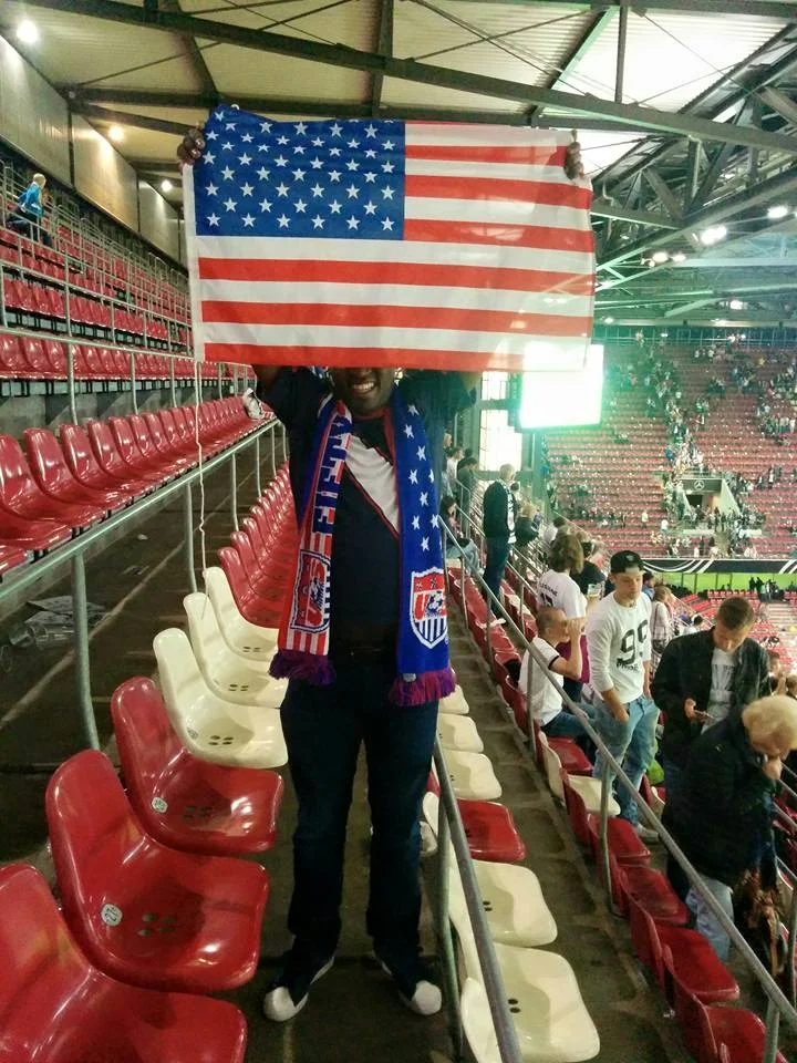 Foto von Jason im Stadion, der eine USA Flagge hochhält.