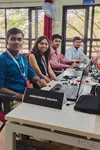 A group of three men and one woman are looking at the camera. They are sitting at a desk with computers and cables and a sign that reads “Innovision Squad.”