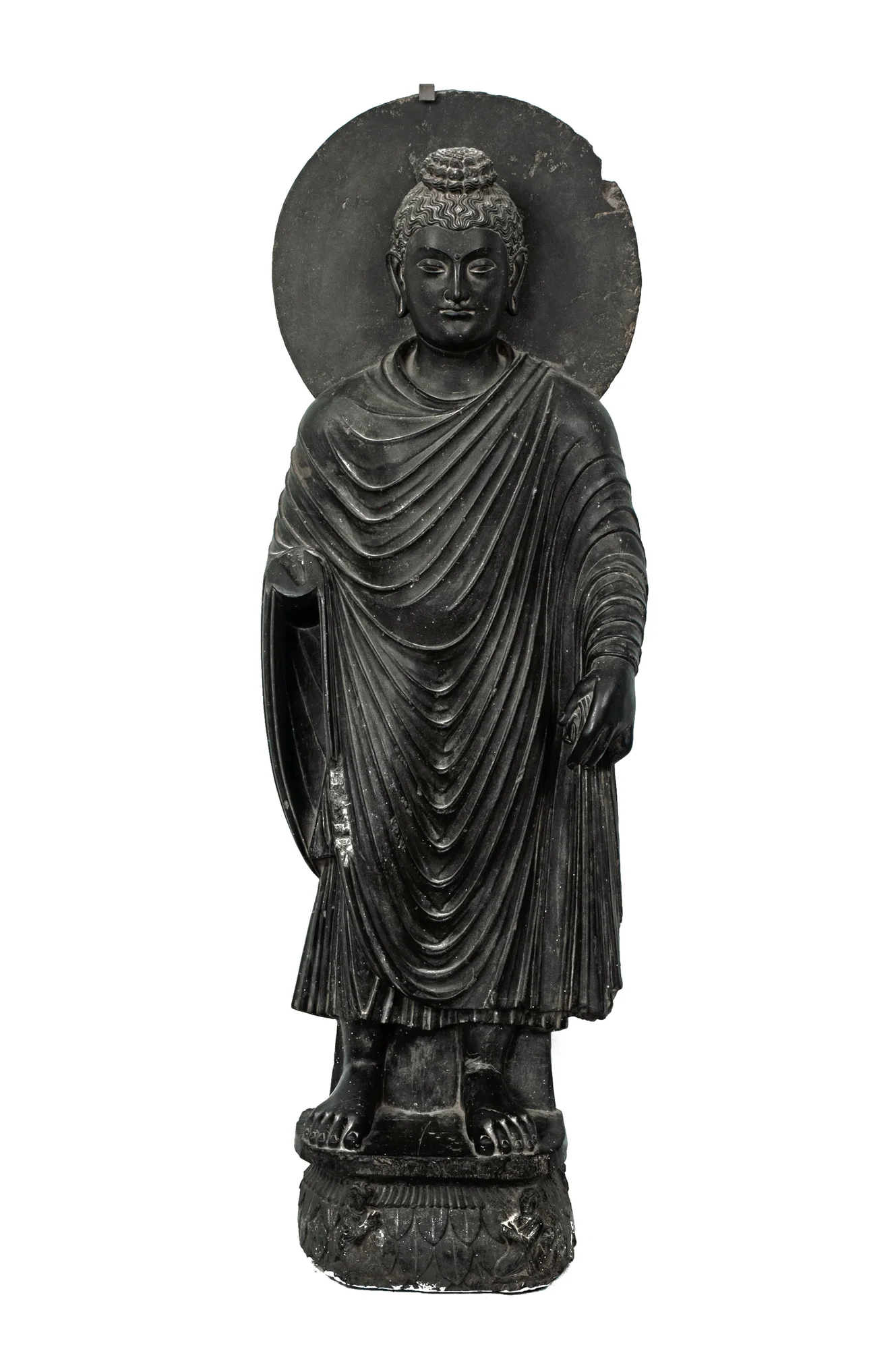 Color photograph of a dark grey statue of a person in a robe with their eyes closed, standing barefoot with a flat circle behind their head, against a white background.