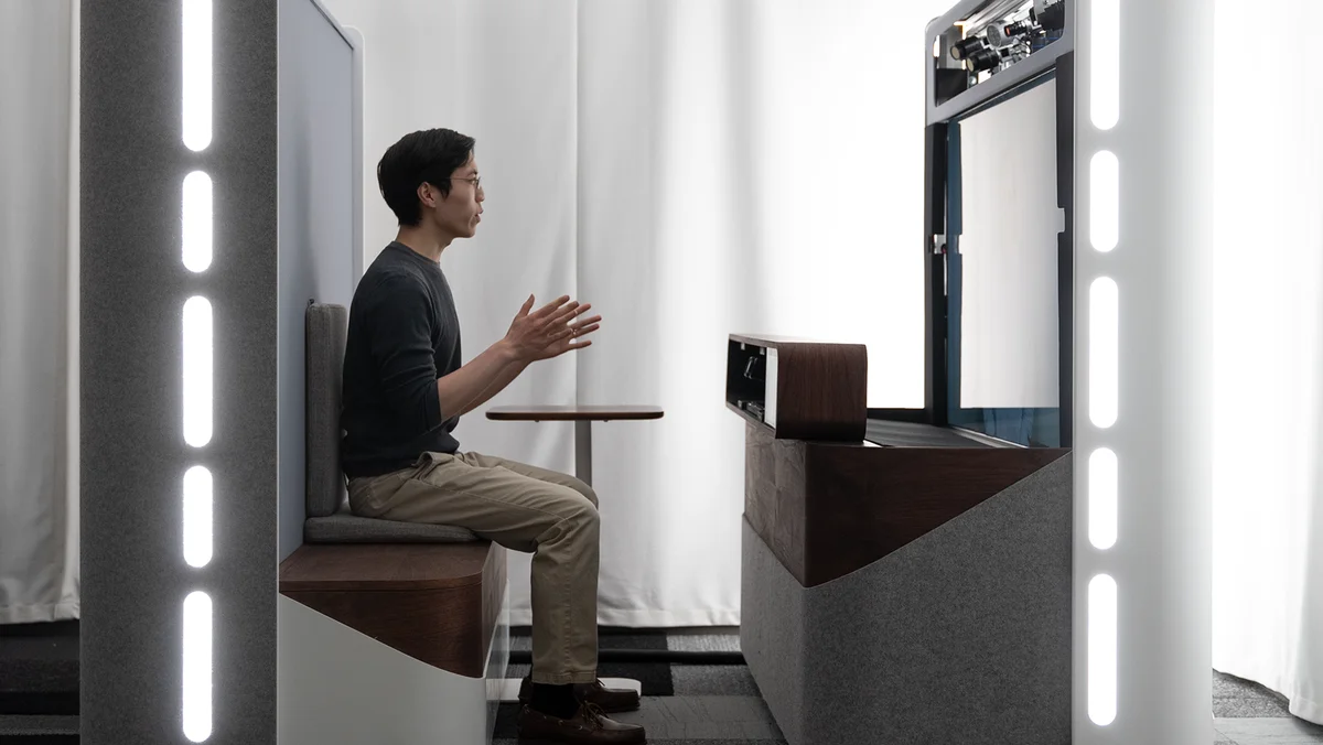 A man sits in a booth using Project Starline on a call.