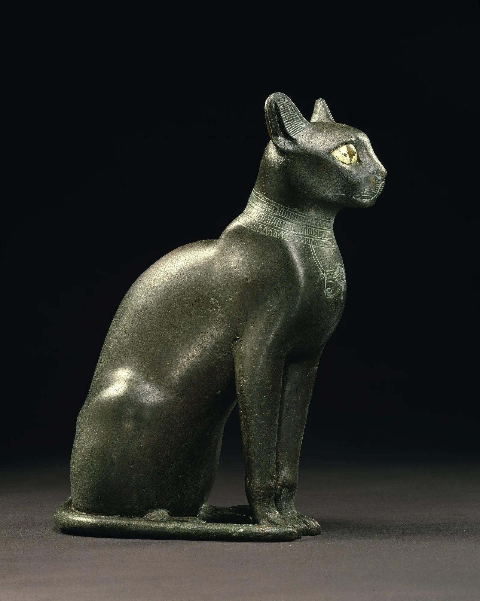 A seated side profile of a black cat statue, with brightly painted eyes.