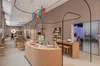 A person in a green sweater stands at a wooden desk inside Google’s retail store.