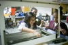 Three students learning how to use a laser cutter.