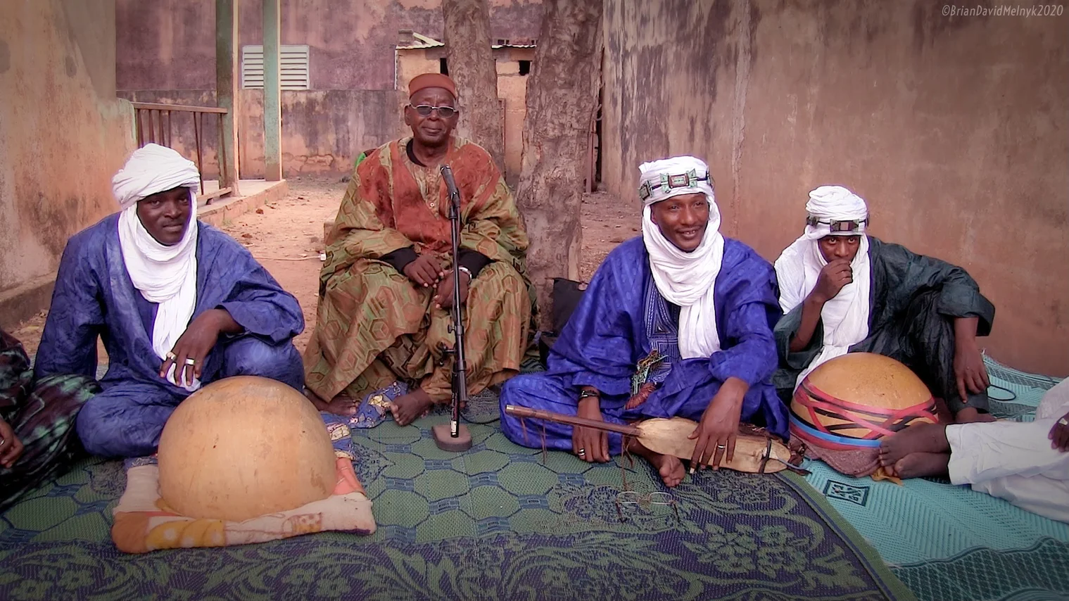 A group of Malian musicians sit with traditional instruments.