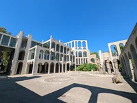 A carousel of four photos. The first shows a large courtyard with a building made of various levels and columns in the background.