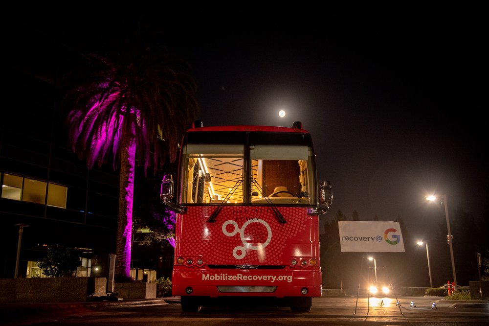 Mobilize Recovery bus parked next to Google campus, lit purple in celebration of recovery month