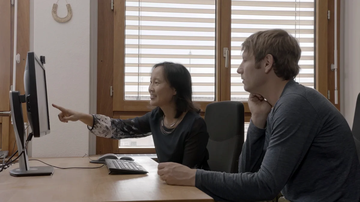 Google.org Fellow Grace Kwak Danciu sits next to Friedhelm Weinberg, Executive Director of HURIDOCS, while looking at a computer while they work on machine learning models to automatically catalog human rights documents.