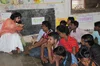 a person sitting on a chair addresses a group of men sitting on the ground in a classroom.