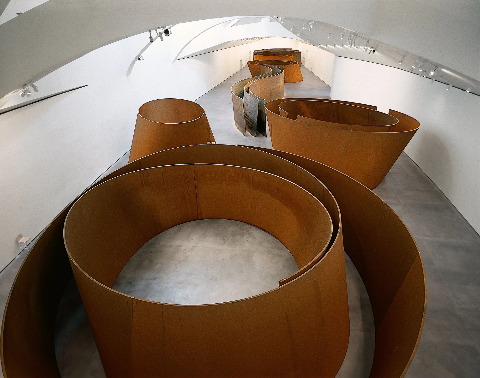 Giant sculpture of curved steel plates covering the entire space of a room. The photograph has a zenithal perspective, so we see the top of the sculptures.