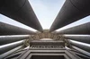 A bottom view looking up at columns circling the view around a high standing building.