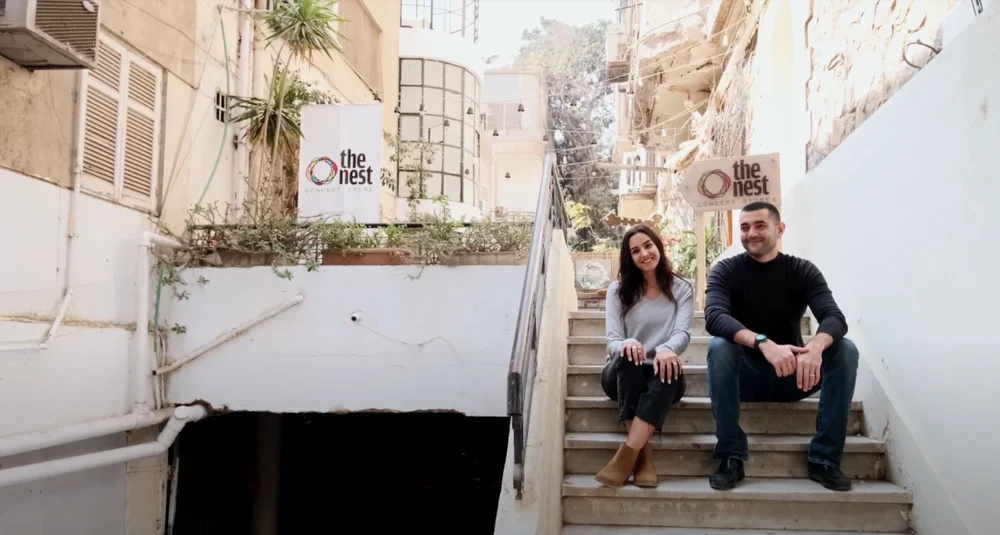 Dina and Omar, founders of The Nest, sit on some steps outside their store in Cairo, Egypt