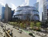 A rendering of a large, modern glass building with a curvilinear facade - the redesigned Thompson Center - on a busy Chicago street corner.