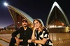Image of two people sitting side by side on the steps in front of the Sydney Opera House
