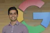 Reza smiling indoors in front of large "G" sculpture.