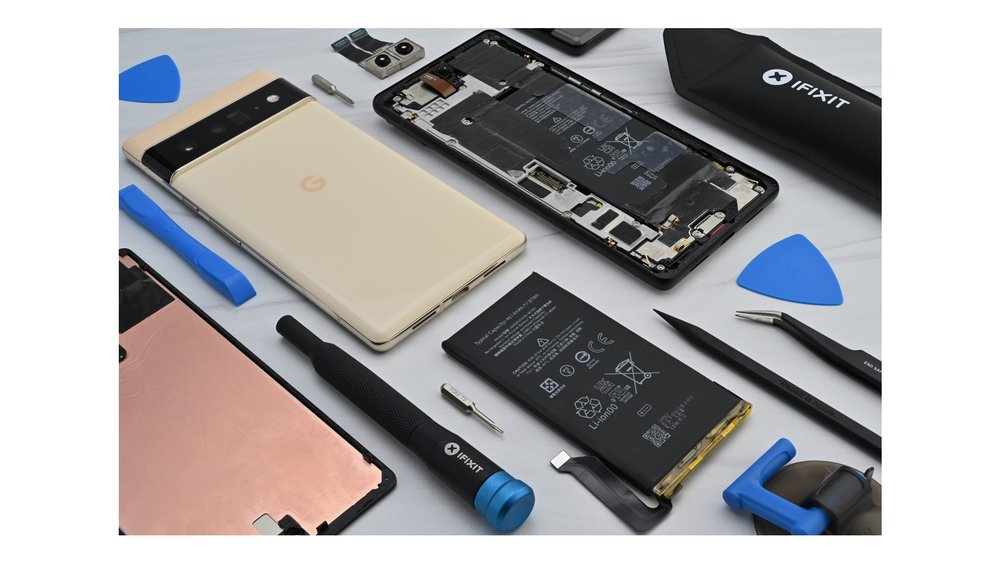 A Sorta Sunny color Pixel 6 Pro lies face-down on a table next to a variety of spare parts and iFixit-branded repair tools.