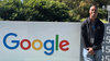 Jerry stands outside next to a sign with the Google logo.