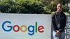 Jerry stands outside next to a sign with the Google logo.