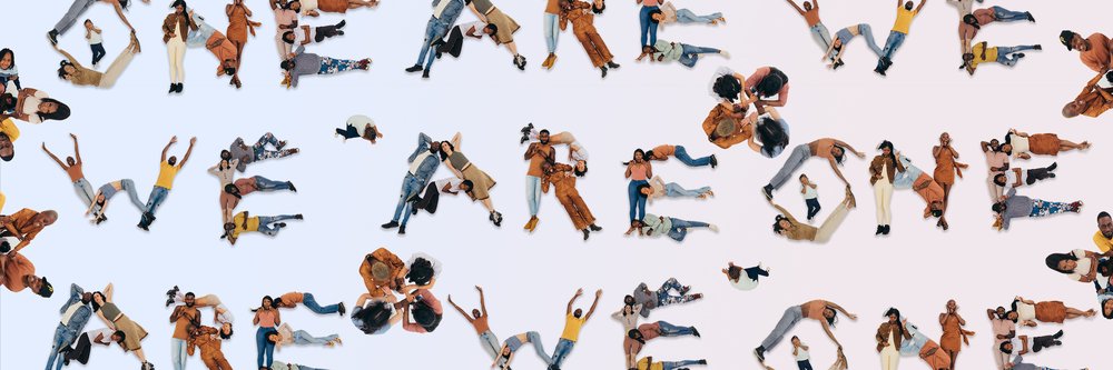 Photograph showing people laying down to write out the words "We are one."