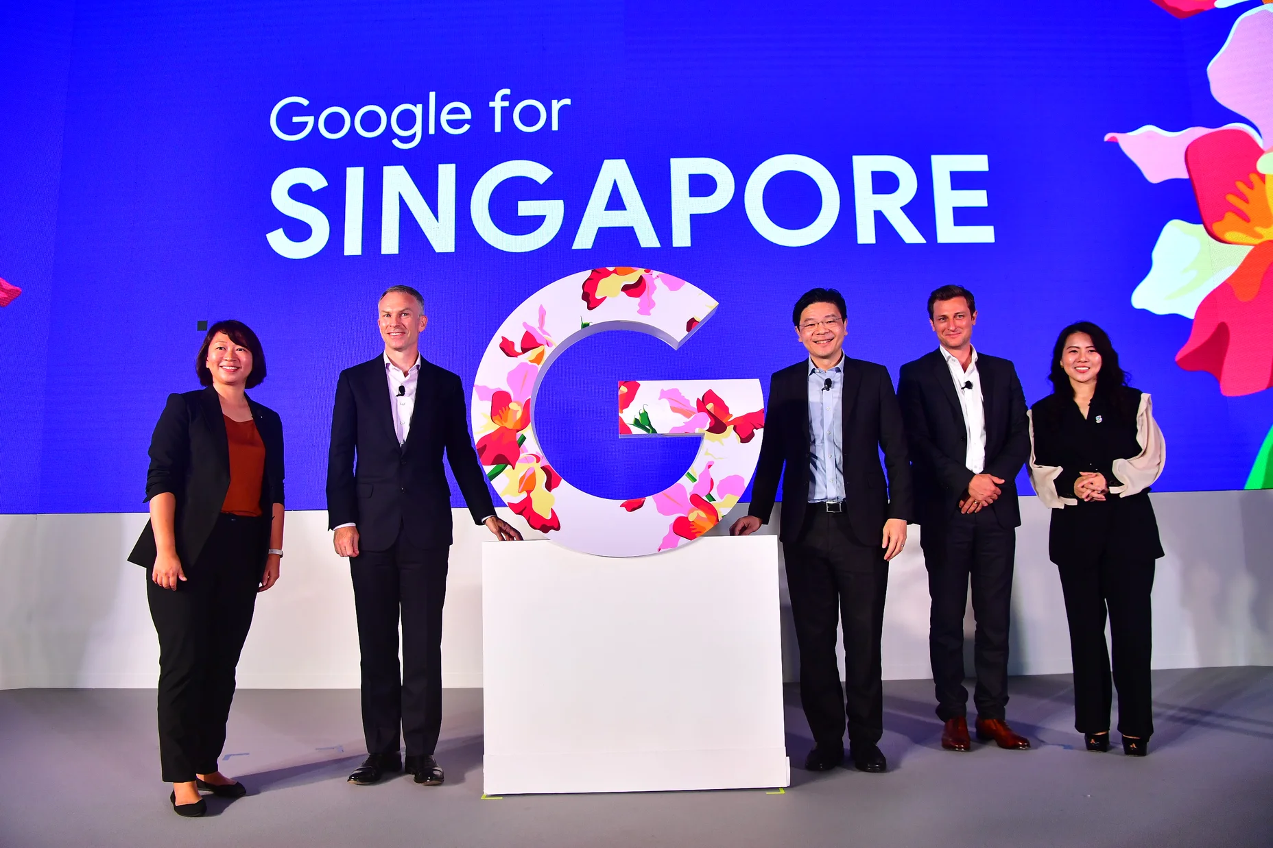 Five people stand on stage next to a pedestal with the letter G. The wall behind them reads: Google for Singapore.
