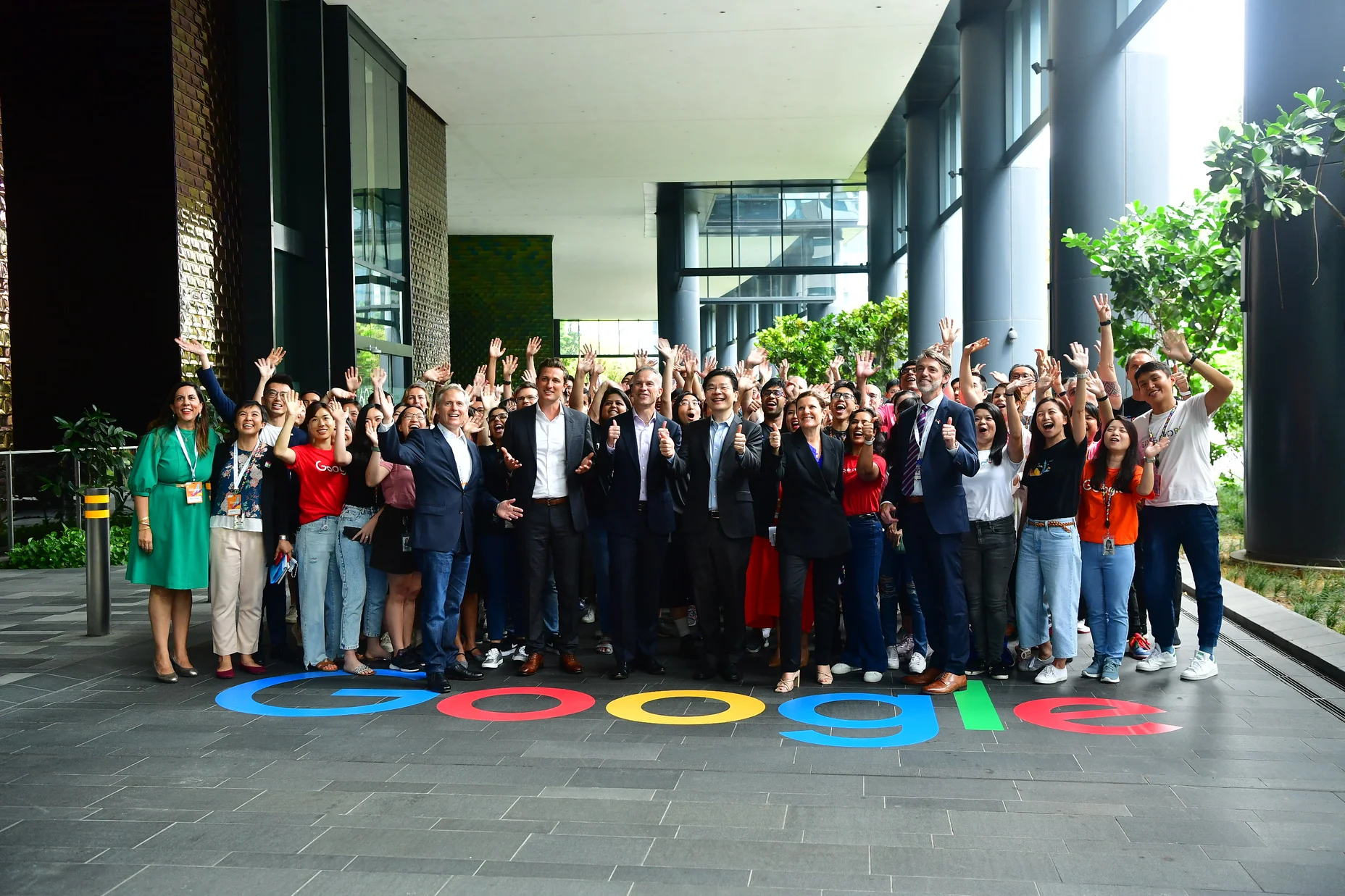 A crowd of people standing outside. The ground they're standing on reads: Google.