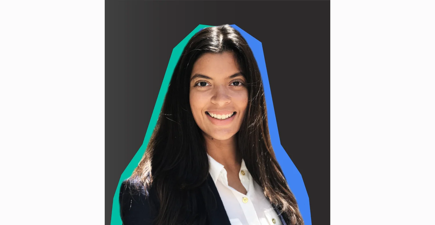 Image shows a woman with dark hair smiling at the camera against a black background.