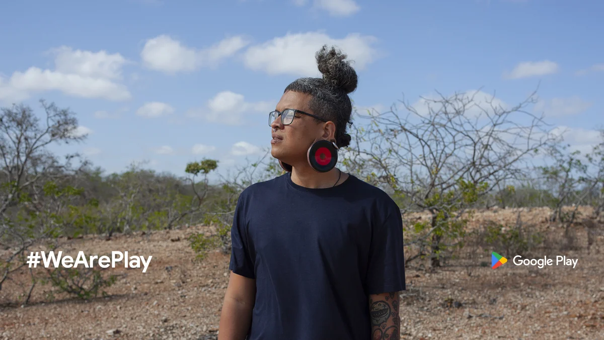 A man stands outside in the desert and looks to the left. The #WeArePlay logo is in the bottom left, and the Google Play logo is in the bottom right.