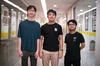 Image shows the three out of four of the Wonder Reader team. Three men are standing in their university, facing the camera, wearing t-shirts and trousers. Their names are Philipus, Jason and Jason.