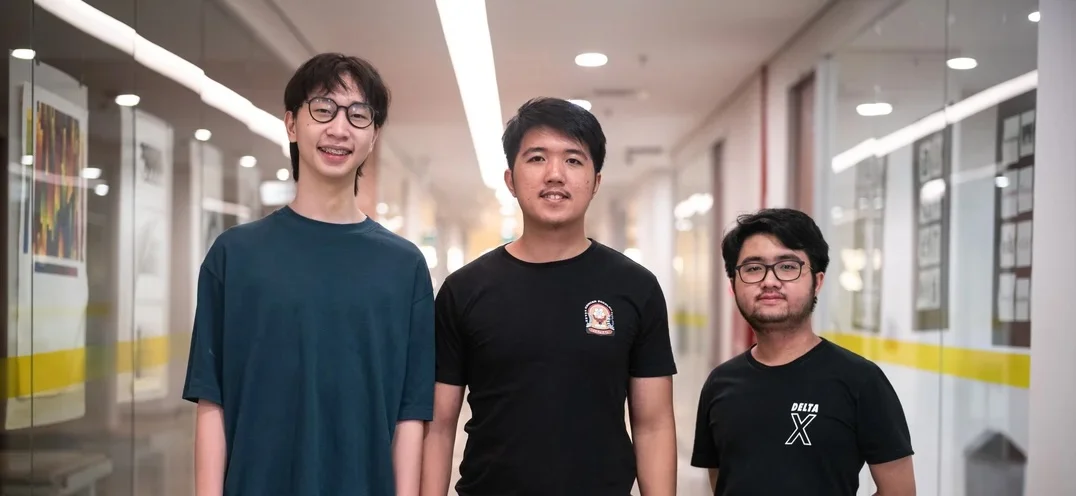 Three people standing in a hallway, looking at the camera