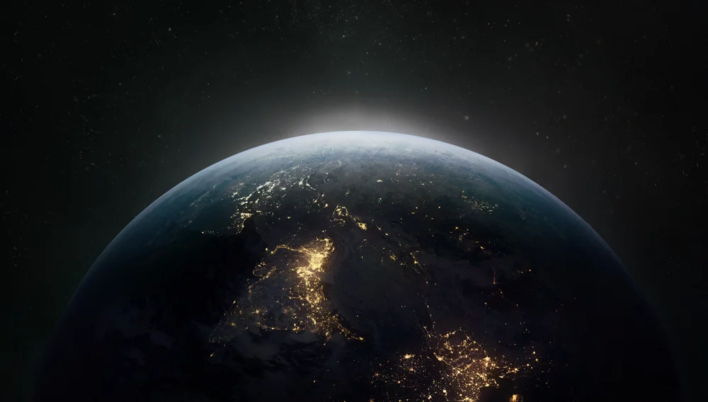 Image of the Earth taken from outer space, with a light emerging from the top of the globe.